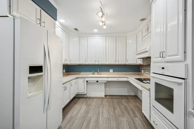 a kitchen with white cabinets and white appliances