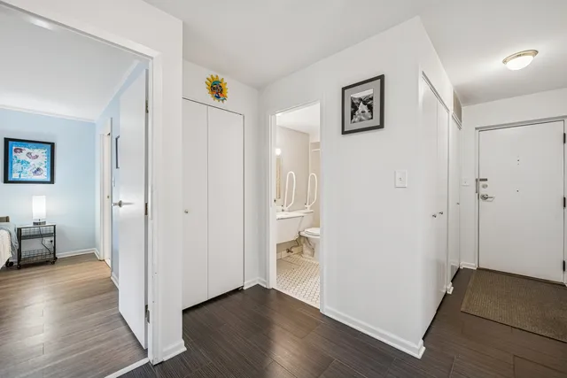 a view of a hallway with wooden floor and a bathroom