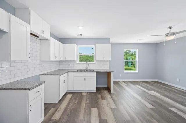 a kitchen with granite countertop a stove sink and cabinets
