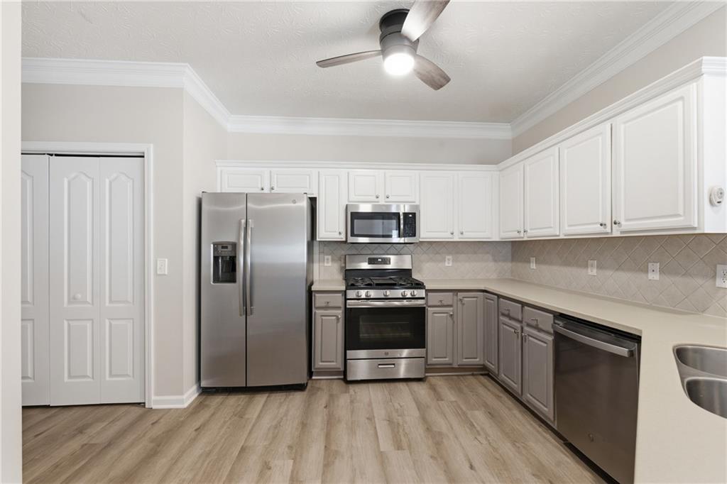 4533 Caleb Crossing, Unit 18 Powder Springs, GA 30127 - Photo 6 of 24 a kitchen with stainless steel appliances granite countertop a refrigerator a sink dishwasher a stove and white countertops with wooden floor