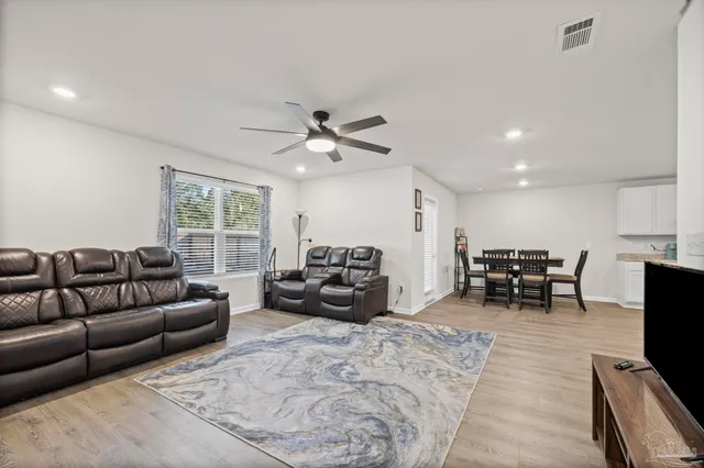 a living room with furniture and a flat screen tv with kitchen view