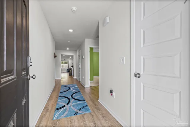 a view of a hallway with wooden floor and a bathroom