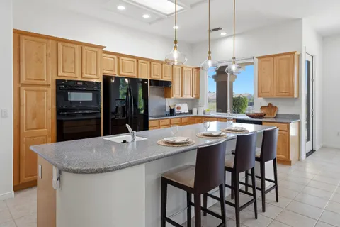 a kitchen with kitchen island granite countertop a stove a sink a oven and a refrigerator