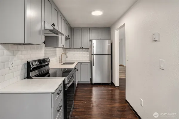 a kitchen with stainless steel appliances a refrigerator a stove a sink and white cabinets with wooden floor