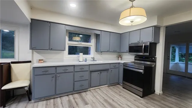 a kitchen with stainless steel appliances granite countertop a sink dishwasher stove and microwave with wooden floor