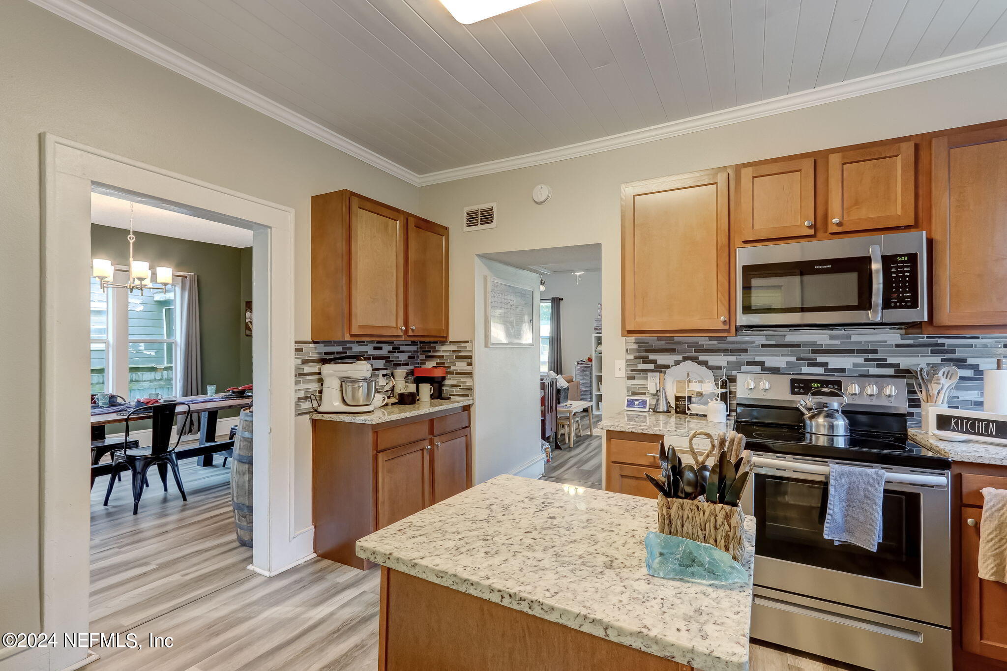 5316 Colonial Avenue Jacksonville, FL 32210 - Photo 14 of 30 a kitchen with stainless steel appliances granite countertop a stove top oven a sink dishwasher a dining table and chairs with wooden floor