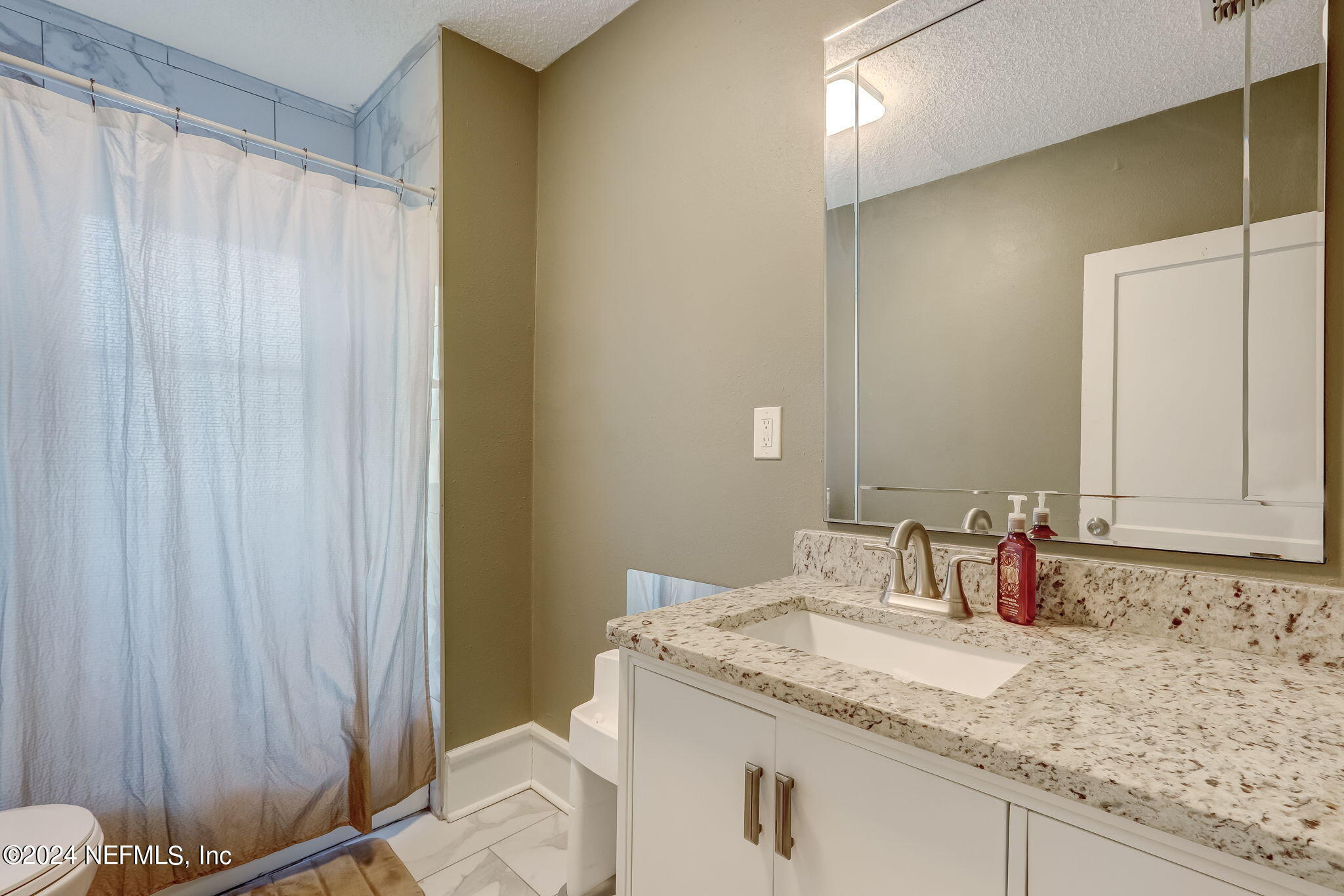 5316 Colonial Avenue Jacksonville, FL 32210 - Photo 26 of 30 a bathroom with a granite countertop sink and a mirror