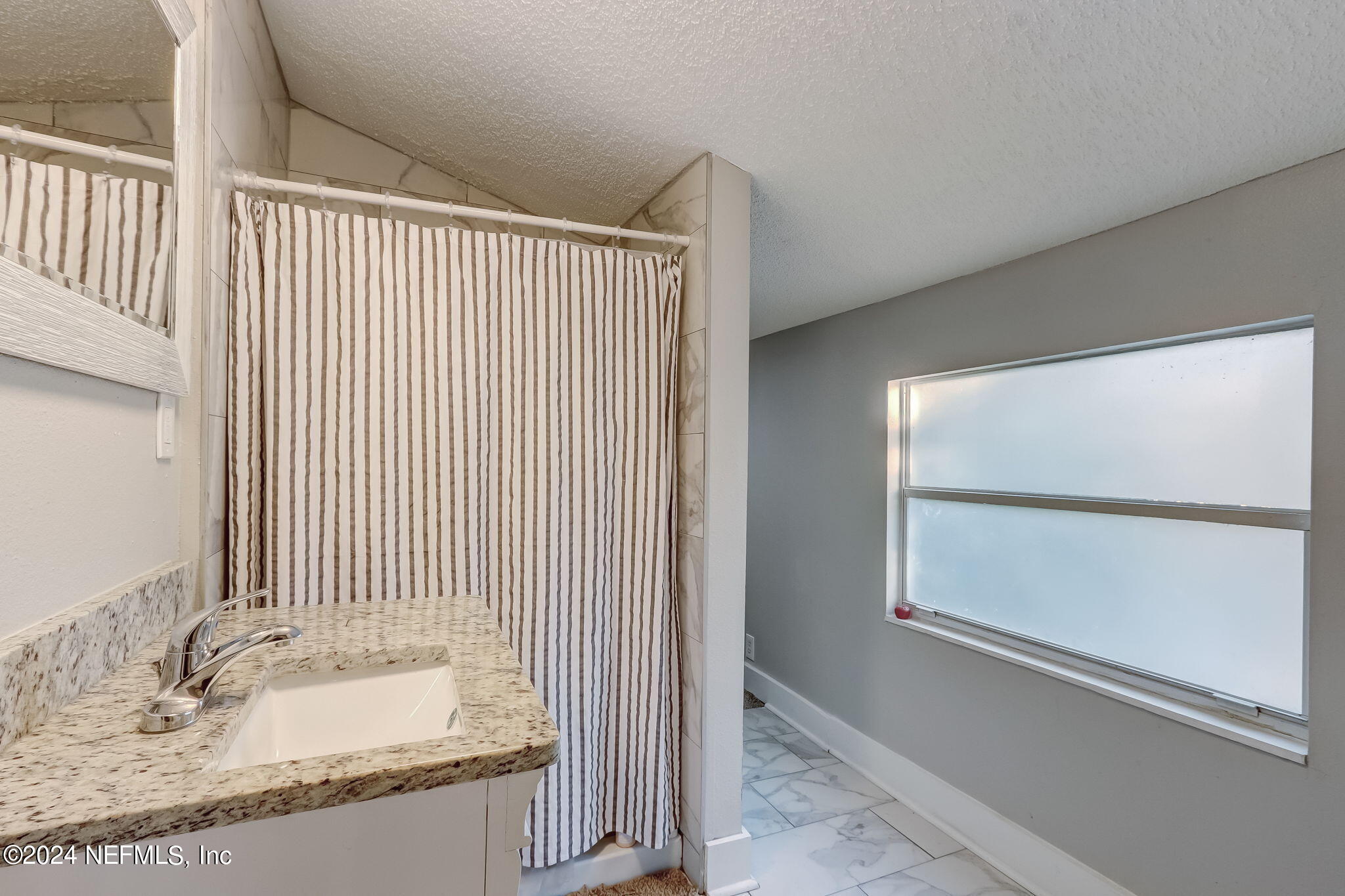5316 Colonial Avenue Jacksonville, FL 32210 - Photo 27 of 30 a bathroom with a granite countertop sink and a mirror