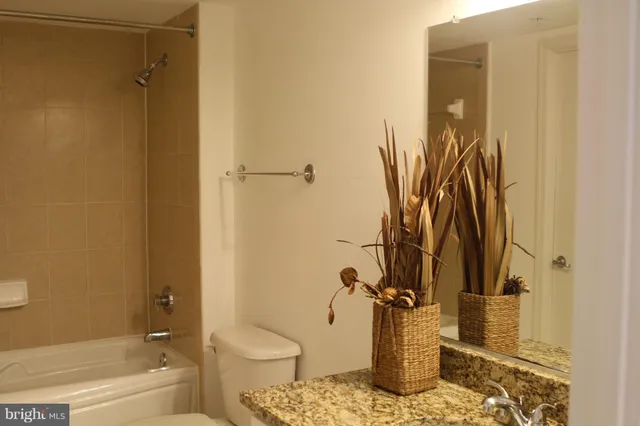 a bathroom with a granite countertop bathtub shower and toilet
