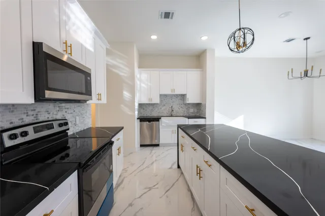 a kitchen with stainless steel appliances granite countertop a sink a stove microwave and cabinets