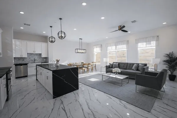 a large living room with stainless steel appliances kitchen island granite countertop a large counter top a sink a window and a couch