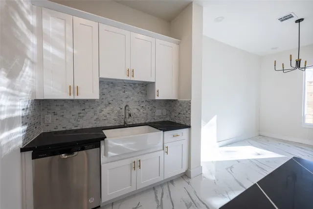 a kitchen with white cabinets and sink