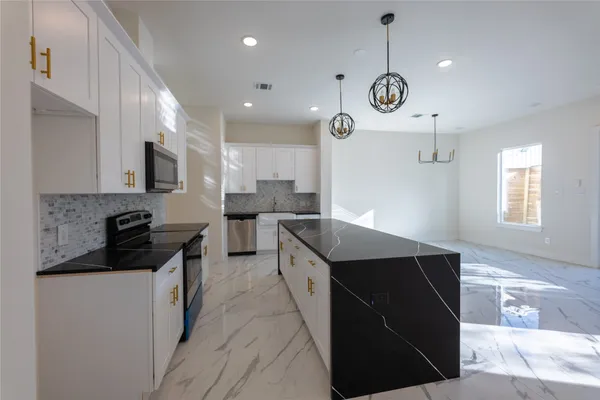 a kitchen with granite countertop a sink a counter top space stove and cabinets
