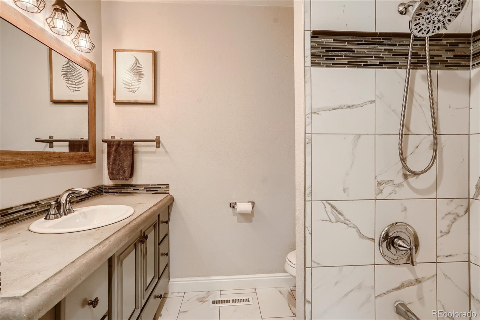 7972 Chase Circle, Unit 82 Arvada, CO 80003 - Photo 8 of 11 a bathroom with a granite countertop sink a mirror and shower