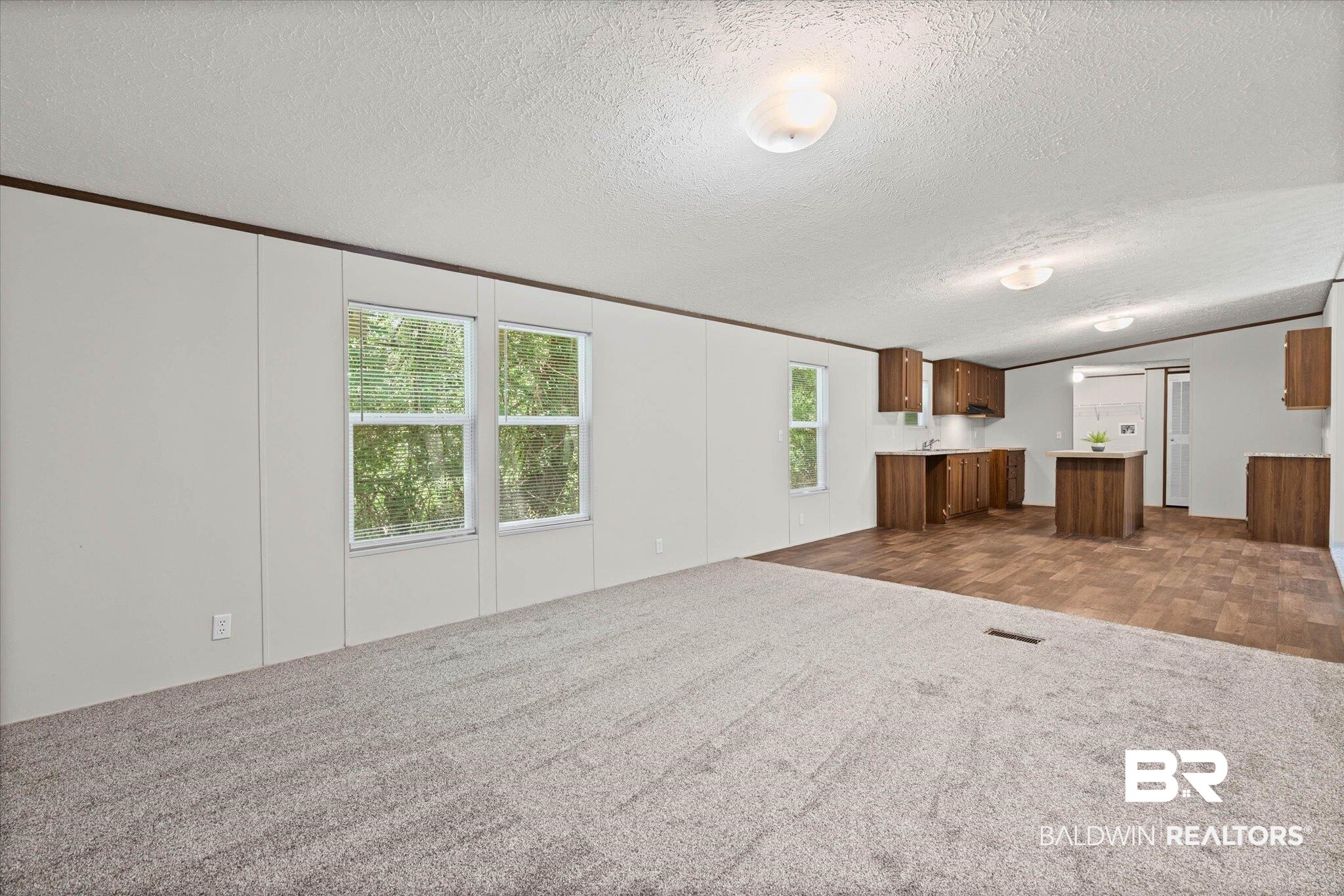 25366 Pollard Road Daphne, AL 36526 - Photo 6 of 22 Open-concept living area featuring a kitchen with wood-finish cabinetry, a central island, and complementary wood-look flooring