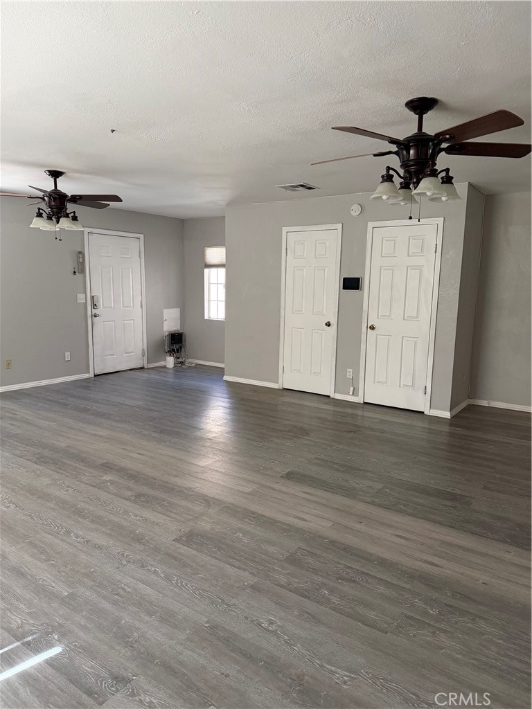18602 Cocqui Road Apple Valley, CA 92307 - Photo 5 of 16 an empty room with wooden floor ceiling fan and windows