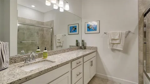 a bathroom with a granite countertop double vanity sink and mirror