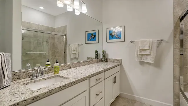 a bathroom with a granite countertop double vanity sink and mirror