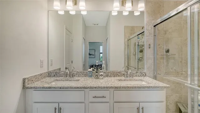 a bathroom with a granite countertop sink a large mirror and a shower