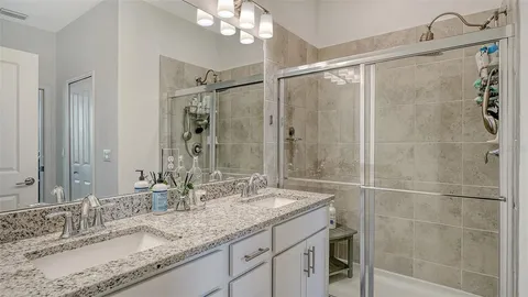 a bathroom with a granite countertop sink a mirror and shower