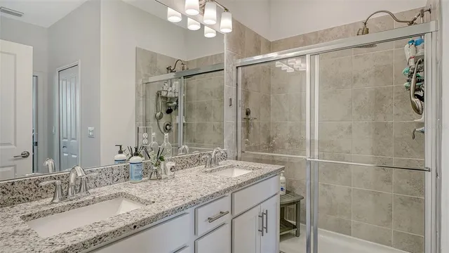 a bathroom with a granite countertop sink a mirror and shower