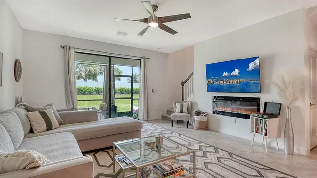 a living room with furniture a ceiling fan and a flat screen tv