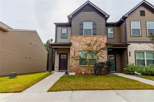 a view of a house with small yard plants and large tree