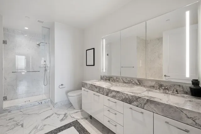 a bathroom with a granite countertop sink a toilet and shower