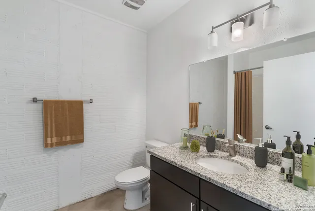 a bathroom with a granite countertop sink a large mirror and toilet
