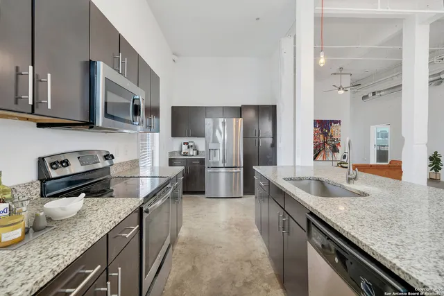 a kitchen with stainless steel appliances granite countertop a sink a stove and a refrigerator