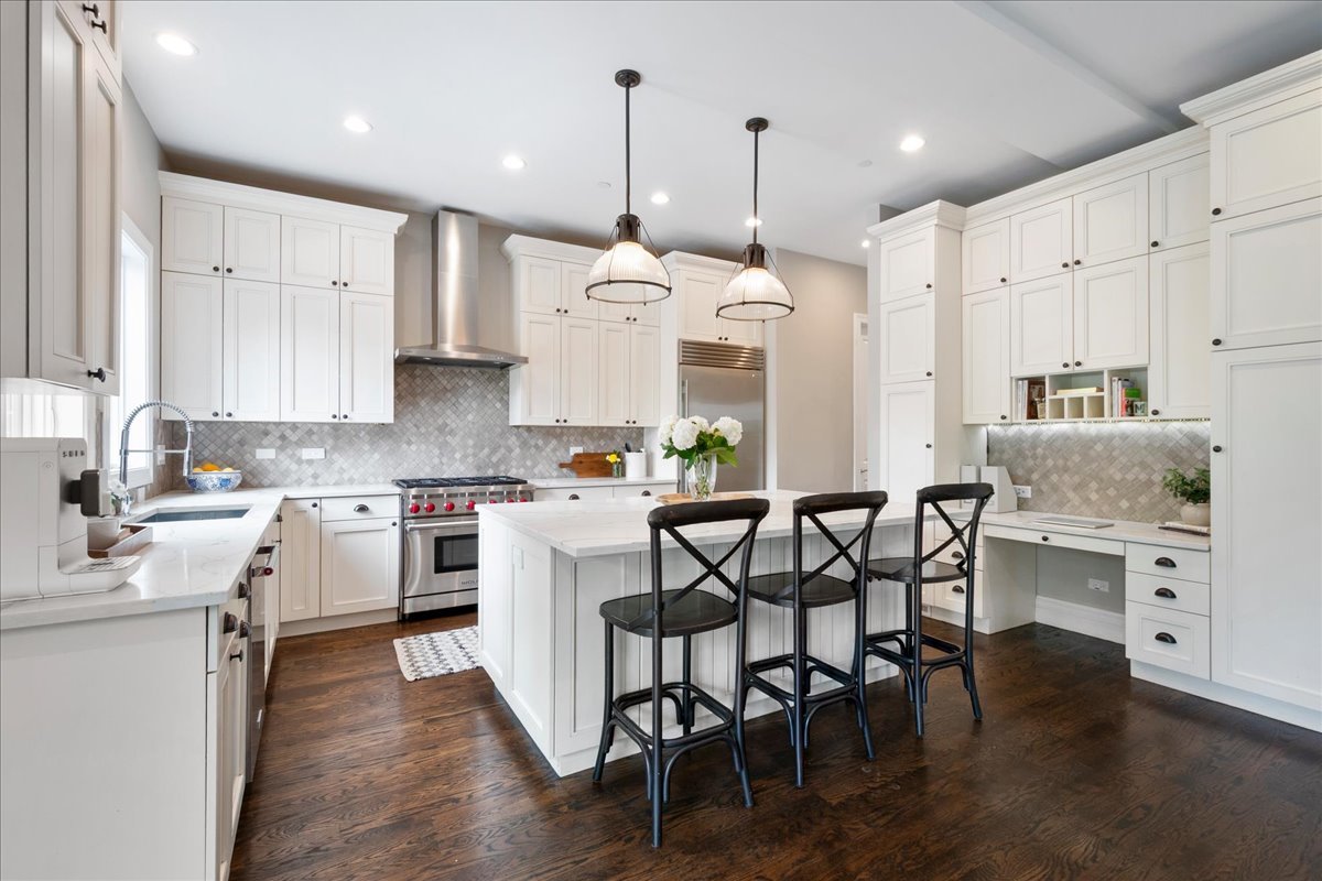 2921 Simpson Street Evanston, IL 60201 - Photo 8 of 41 a kitchen with stainless steel appliances kitchen island a wooden floor and white cabinets