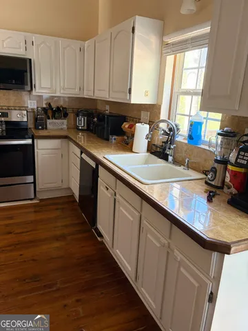 a kitchen with stainless steel appliances granite countertop wooden cabinets a sink and dishwasher with wooden floor