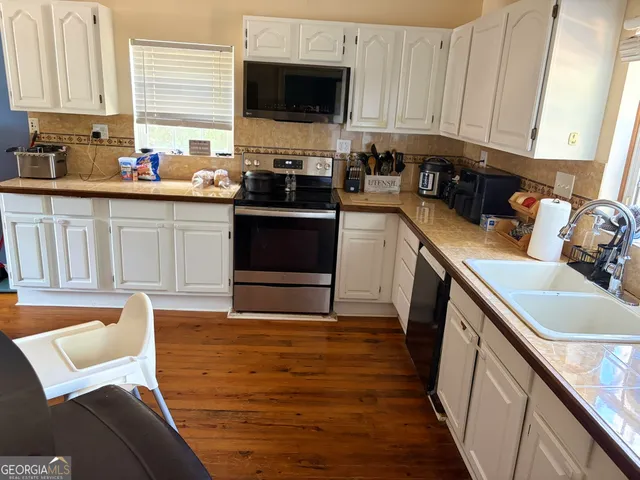 a kitchen with stainless steel appliances a stove top oven a sink a refrigerator a sink and cabinets