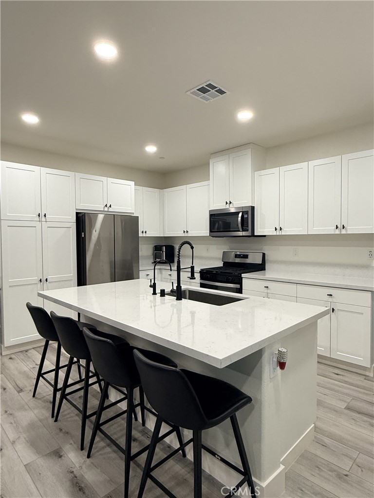 4067 Summer Corona, CA 92883 - Photo 7 of 12 Open-concept kitchen with large island, quartz countertops, stainless steel appliances, and ample cabinet storage.