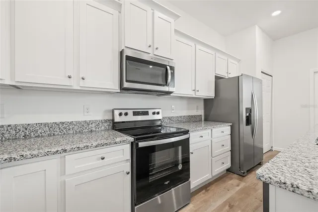 a kitchen with granite countertop a sink and white cabinets
