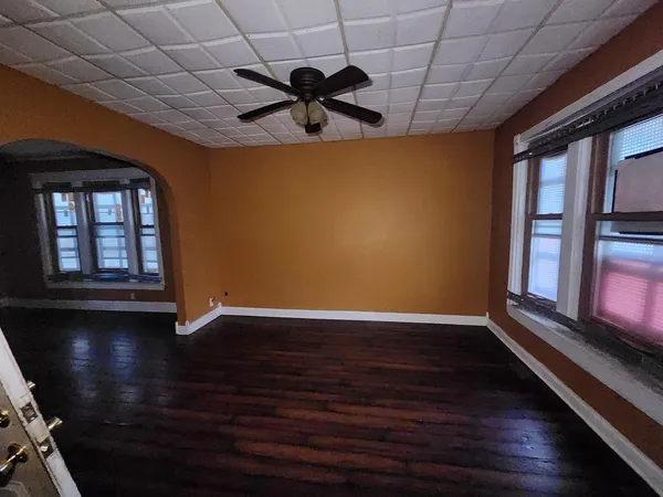 a view of an empty room with a window and wooden floor