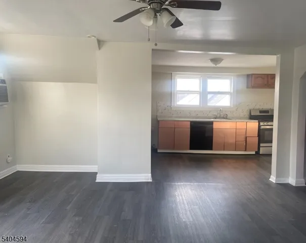 a view of kitchen and empty room with wooden floor