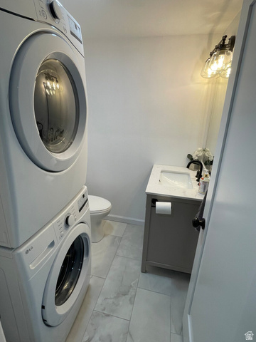 2807 North Ogden Canyon Road Eden, UT 84310 - Photo 32 of 72 Compact laundry area featuring stacked front-load machines, a white toilet, and tile flooring