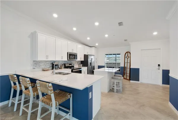 a kitchen with stainless steel appliances kitchen island granite countertop a table chairs and a refrigerator