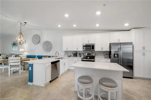 a kitchen with stainless steel appliances granite countertop a sink a stove a refrigerator cabinets and chairs