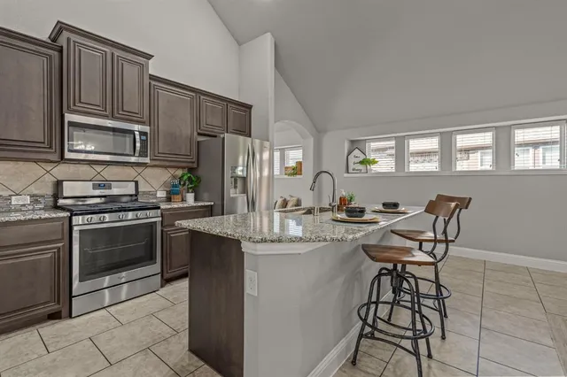 a kitchen with stainless steel appliances granite countertop a stove a sink dishwasher a refrigerator and cabinets with wooden floor