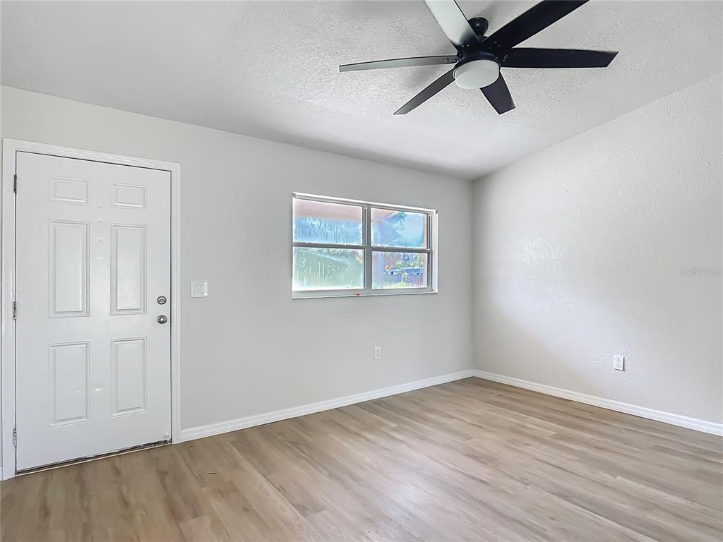6707 Sierra Terrace New Port Richey, FL 34652 - Photo 11 of 50 an empty room with wooden floor ceiling fan and windows