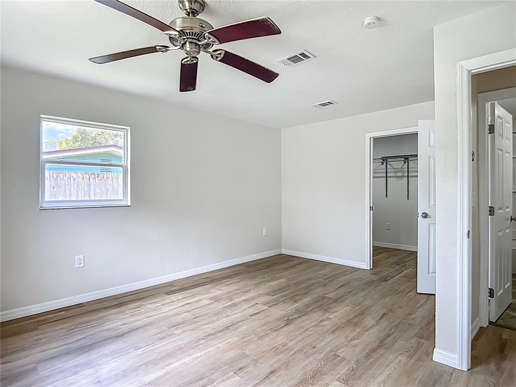 6707 Sierra Terrace New Port Richey, FL 34652 - Photo 21 of 50 an empty room with wooden floor chandelier fan and windows