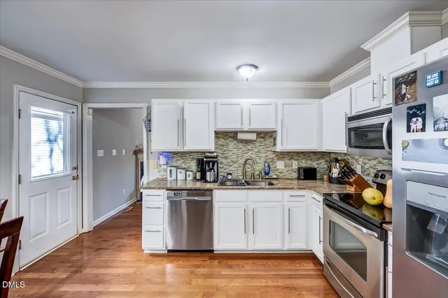 a kitchen with stainless steel appliances granite countertop a stove top oven a sink dishwasher and a refrigerator