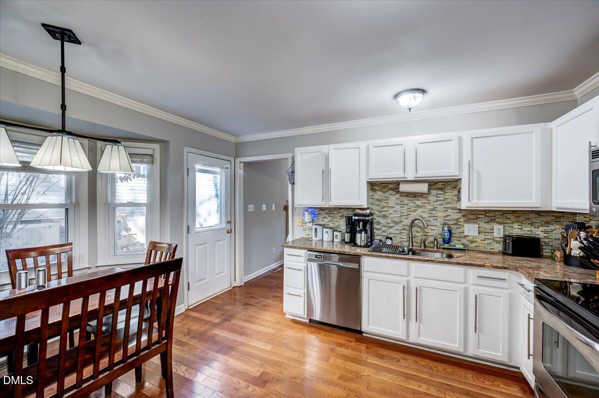 103 Kingsmill Road Cary, NC 27511 - Photo 8 of 30 a kitchen with stainless steel appliances a sink a stove a refrigerator cabinets and a dining table with wooden floor