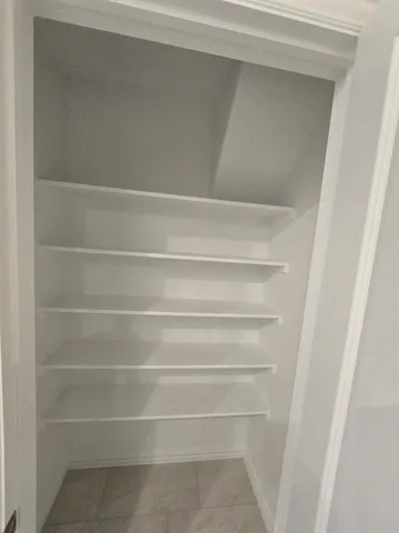 an empty room with a chandelier fan and windows