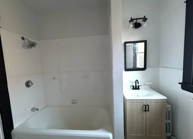 a bathroom with a bathtub shower sink and mirror