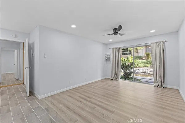 a view of an empty room with wooden floor and a window