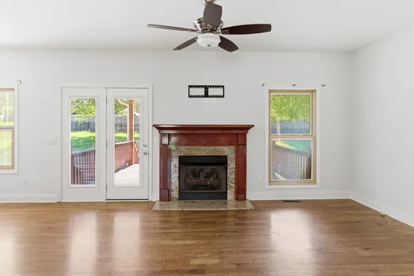 a view of an empty room with wooden floor fireplace and a window
