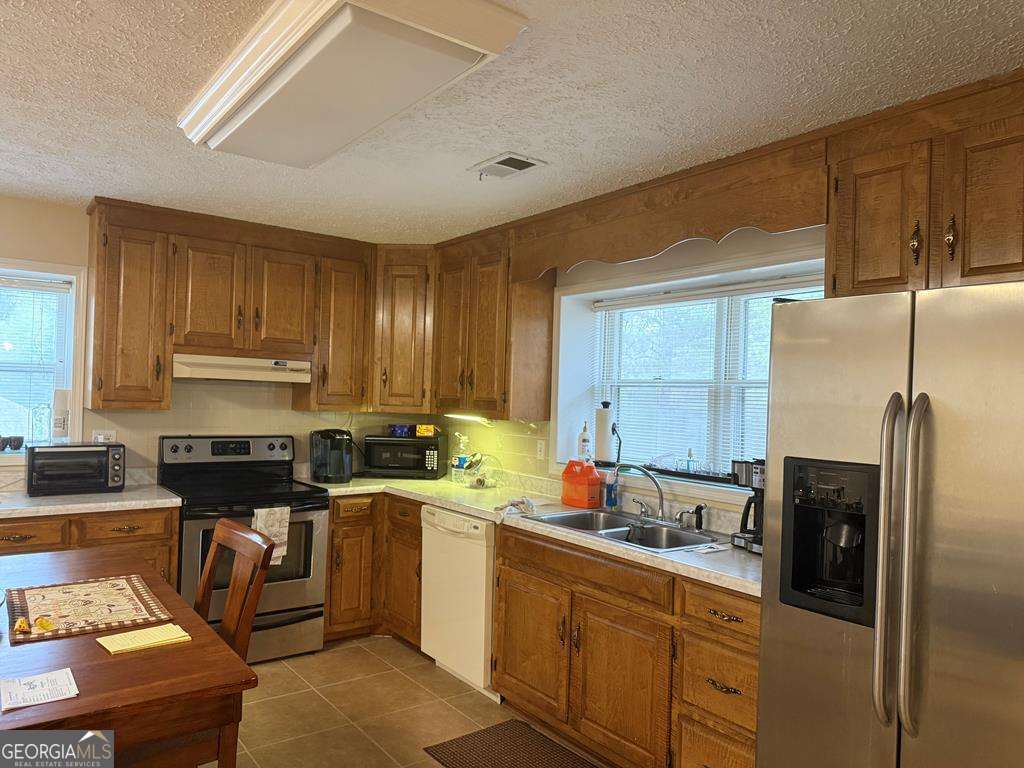 1837 Whooping Creek Road Carrollton, GA 30116 - Photo 3 of 19 a kitchen with stainless steel appliances granite countertop a stove a sink dishwasher and a refrigerator with wooden cabinets